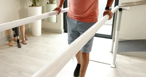 Man in prosthetic leg walking using parallel bars for rehabilitation therapy Stock-Footage 298144553
