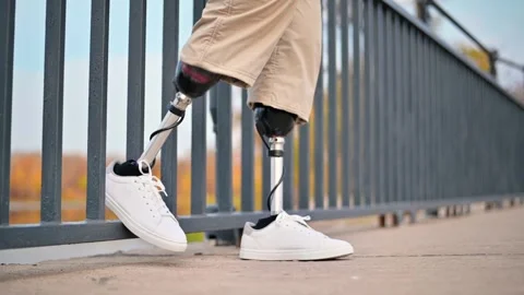 Man with prosthetic legs walking across a bridge in autumn. Stock Footage 339751686