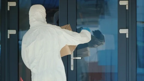 A man in a protective antiviral suit knocks on the door of the house. Quarantine Stock Footage 127047028