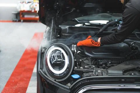Man in protective black gloves drying up the engine with microfibre orange cloth Stock Photos