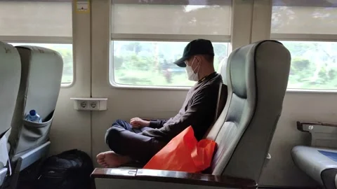 A man in protective face and black cap mask slept inside an intercity train Video stock 164708173