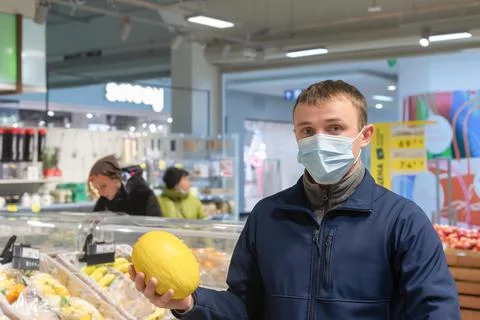 A man in a protective face mask with a melon in his hand. Quarantine. Lifesty Stock Photos