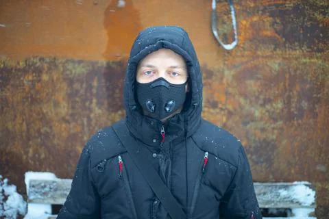 Man with protective face mask sitting on during heavy snowfall Stock Photos