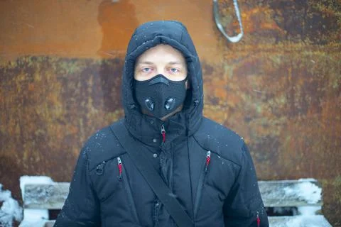 Man with protective face mask sitting on during heavy snowfall Stock Photos
