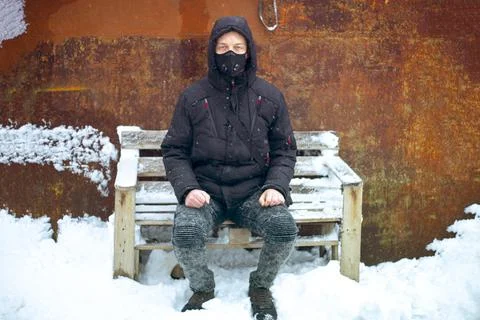 Man with protective face mask sitting on during heavy snowfall Stock Photos