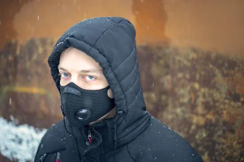 Man with protective face mask sitting on during heavy snowfall Stock Photos