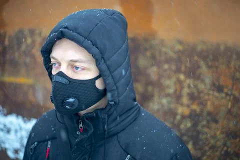 Man with protective face mask sitting on during heavy snowfall Stock Photos