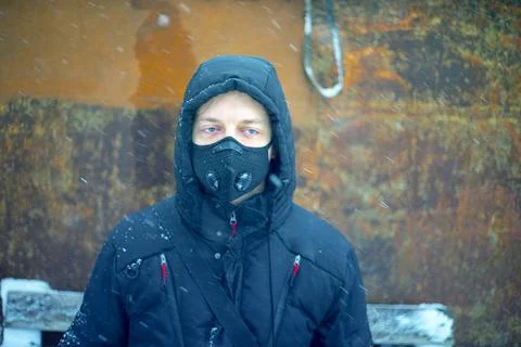 Man with protective face mask sitting on during heavy snowfall Stock Photos