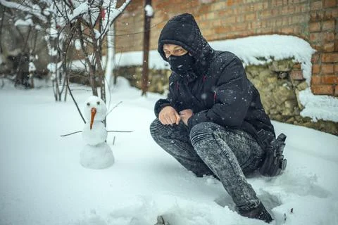 Man with protective face mask sitting on during heavy snowfall Stock Photos