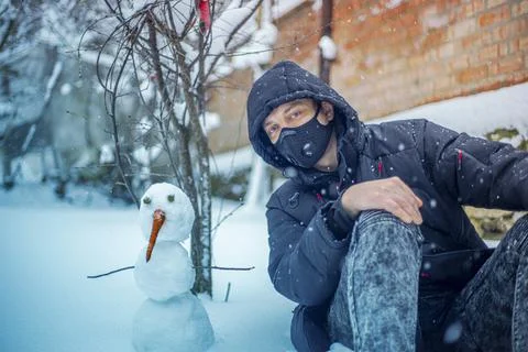 Man with protective face mask sitting on during heavy snowfall Stock Photos
