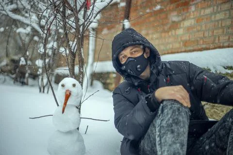 Man with protective face mask sitting on during heavy snowfall Stock Photos