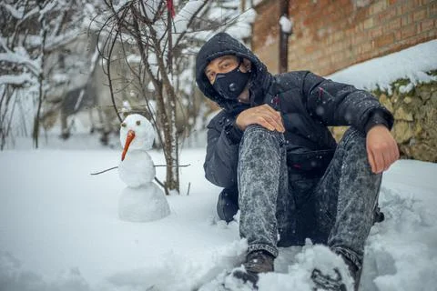 Man with protective face mask sitting on during heavy snowfall Stock Photos