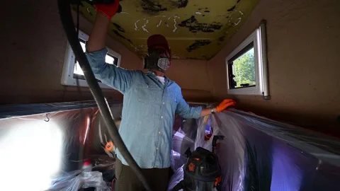 Man with protective gear sanding the ceiling of a camper van 库存影片 347636968