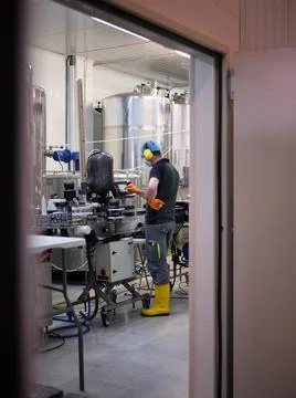 Man with protective gear working with an electronic device in a brewery Stock Photos