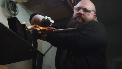 Man in protective glasses processes metal pipe with sandpaper attached to an Stock Footage 189762442