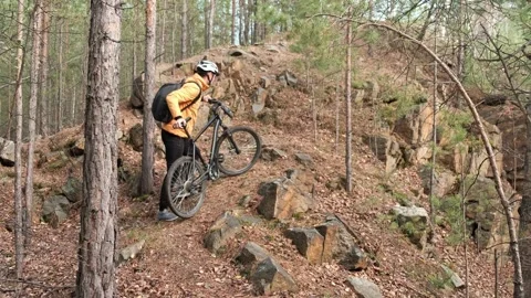 Man in a protective helmet climbs with a mountain bike uphill Video stock 253983764