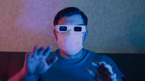 A man in a protective mask and stereo glasses watches TV waving his hands. Stock Footage 130896223