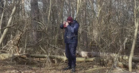 Man in a protective mask in a beautiful pine forest takes pictures with a fi Vídeos de archivo 166439365