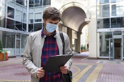 A man in a protective mask with a document in his hands, against the background Stock Photos