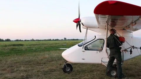 Man in protective mask refueling small white aircraft on grassy airfield 動画素材 313482175