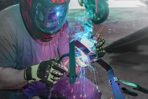 A man in a protective mask works with a welding tool for metal, the reconst.. Stock Photos