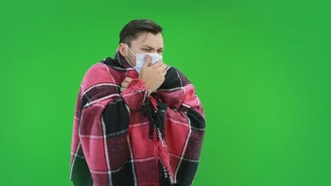 A man in a protective mask, wrapped in a checkered gown, has a coughing illness Video stock 127239690