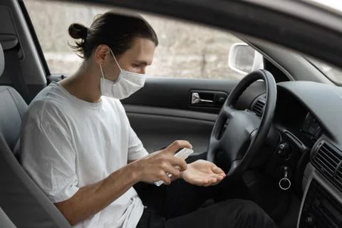 Man in protective medical mask is using antiseptic for protect himself from Stock Photos