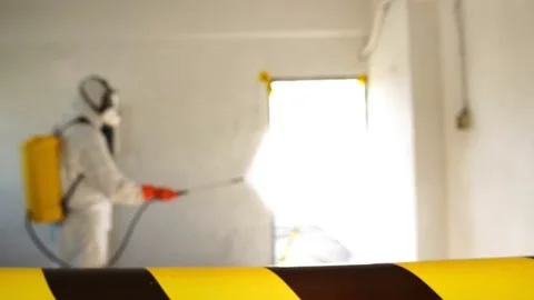 Man in protective suit and face mask spraying for disinfection in the office Stock Footage 148098438