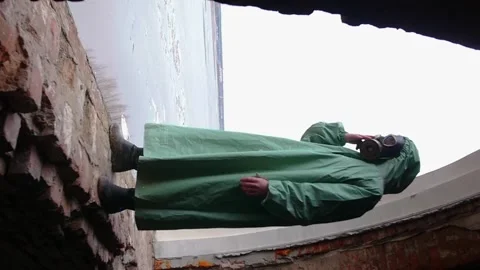 A man in a protective suit and a gas mask standing in the arch of a window of an Stock Footage 304031267