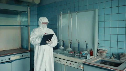 A man in a protective suit and glasses holds a folder with documents in the Stock Footage 131460587