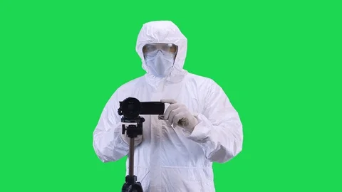 A man in a protective suit and goggles is filming a video camera with a tripod Stock Footage 128756997