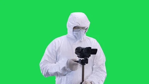A man in a protective suit and goggles is filming a video camera with a tripod Stock Footage 129057785