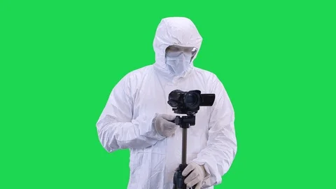 A man in a protective suit and goggles is filming a video camera from a tripod Stock Footage 129194229