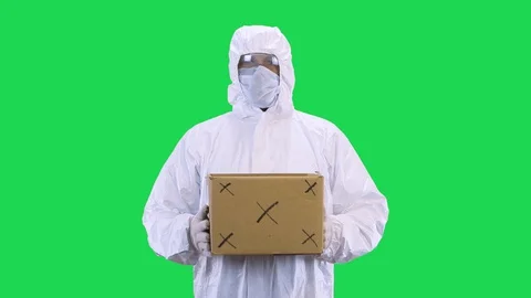 A man in a protective suit and a protective mask and glasses holds a box with Stock Footage 127935018