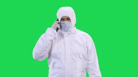 A man in a protective suit and a protective mask and glasses is talking on the Stock Footage 128060595