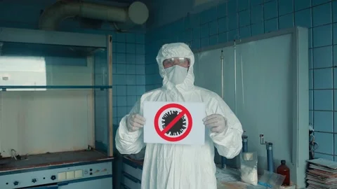 A man in a protective suit and protective mask showing with a sign to stop the Stock Footage 131028009