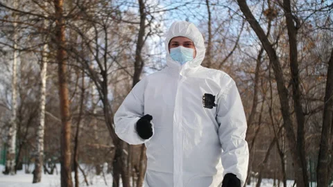 A man in a protective suit performs a dance in the middle of a winter forest. Stock Footage 168869443