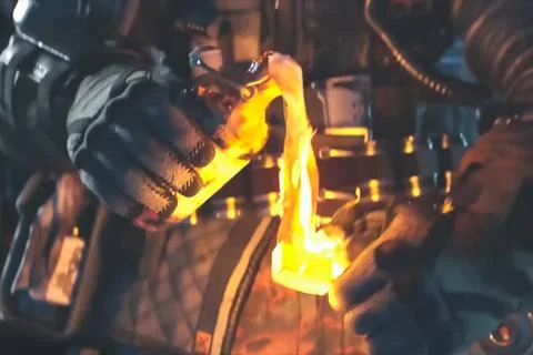 Man in a protective suit sets fire to a Molotov cocktail. Stock Photos