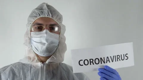 A man in a protective suit shows the name coronavirus 4K Stock Footage 126806745
