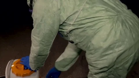 A man in a protective suit. Street sterilization. Disinfection. Covid 19 Stock Footage 128545800