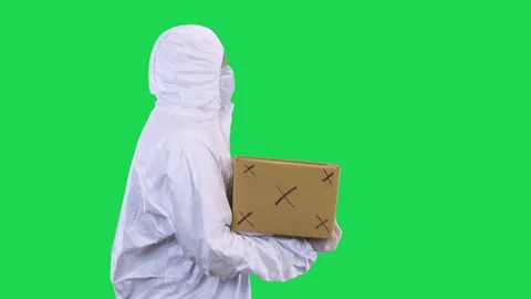 A man in a protective suit walks in a protective mask and glasses carries a box Stock Footage 128060388