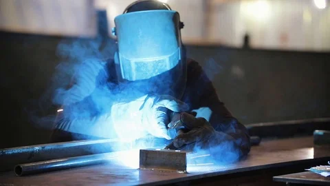 A man in a protective suit works with a welding machine. Bright light Stock Footage 108917649