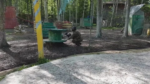 Man in protective uniform and mask sits in ambush with gun then stands up to Video stock 76651165