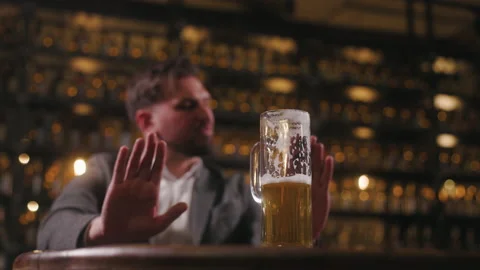 A man in a pub refuses to drink anymore. The beer glass is in focus, with the Stock Footage 237601900