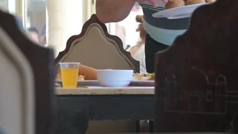 A man in a public dining room puts food on the table, the middle plan. A restaur Stock Footage 164678328