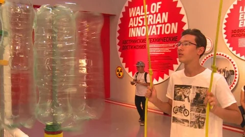 Man pull ropes string and plastic bottles spin in Expo 2017 Austrian pavilion Stock Footage 78690742