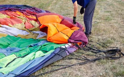 A man is pulling apart a large colorful parachute Stock Photos