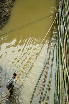 Man pulling bamboo logs from the river Foto stock
