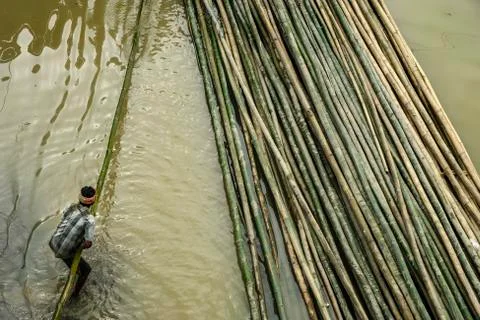 Man pulling bamboo logs from the river Stock Photos