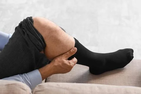 Man pulling up black sock on leg while sitting Stock Photos